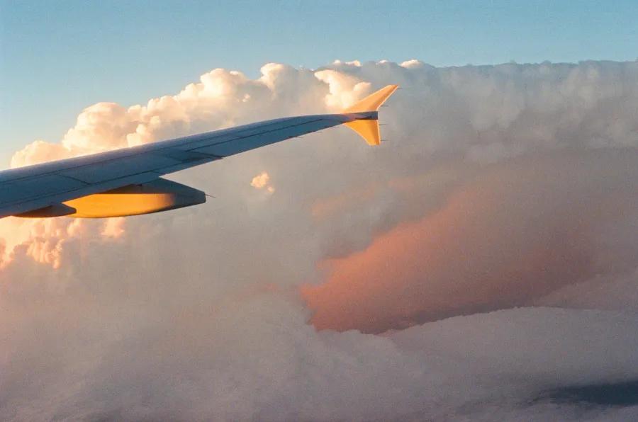 An airplane wing above clouds at sunset